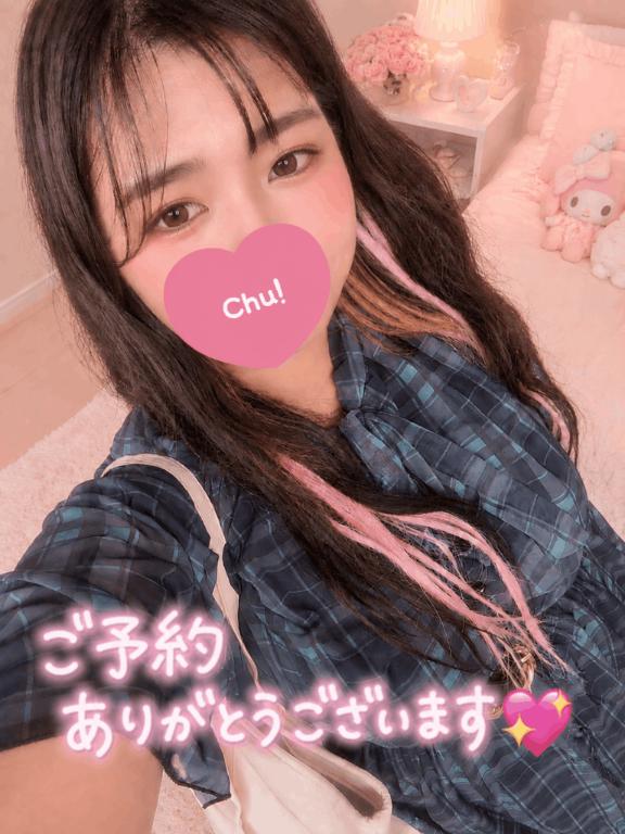 青緑のチェック柄衣装で自撮りし、口元をピンクのハートで隠したロングヘアのぽっちゃり女性