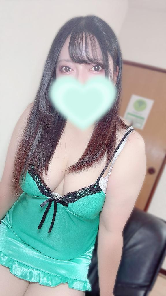 ミントグリーンのサテンキャミソールを着て、口元を淡い緑のハートで隠した黒髪の女性