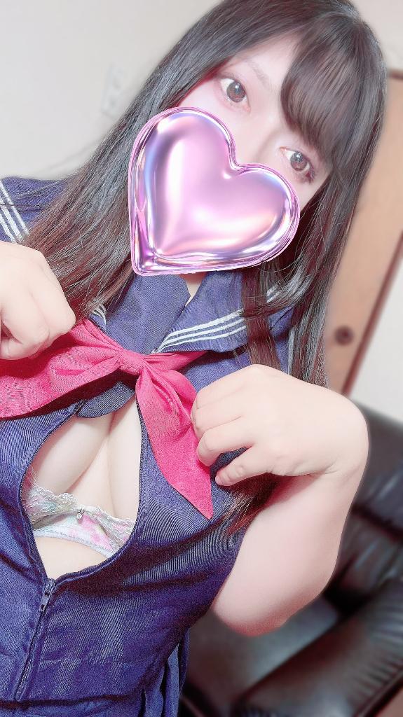 紺色のセーラー服風衣装に赤いリボンを合わせ、口元をピンクのハートで隠した黒髪の女性