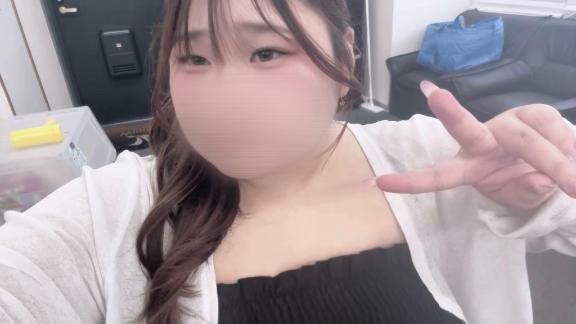 黒いトップスと白いカーディガン姿でピースサインをする、口元をぼかした女性の自撮り