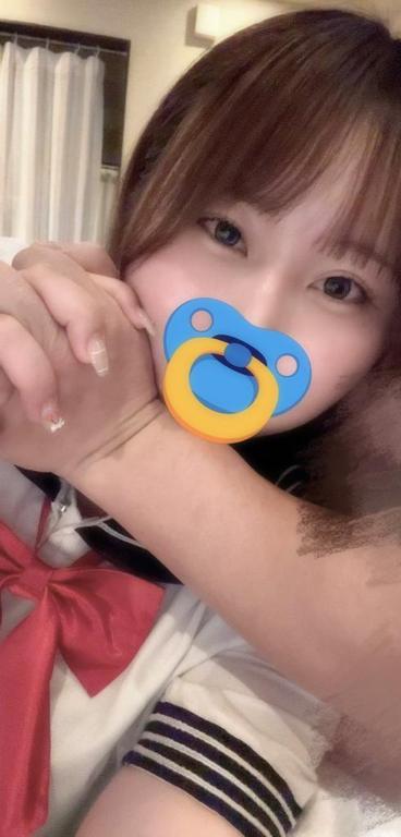 口元を青いスタンプで隠し、赤いリボンのセーラー風衣装姿で両手を重ねた女性
