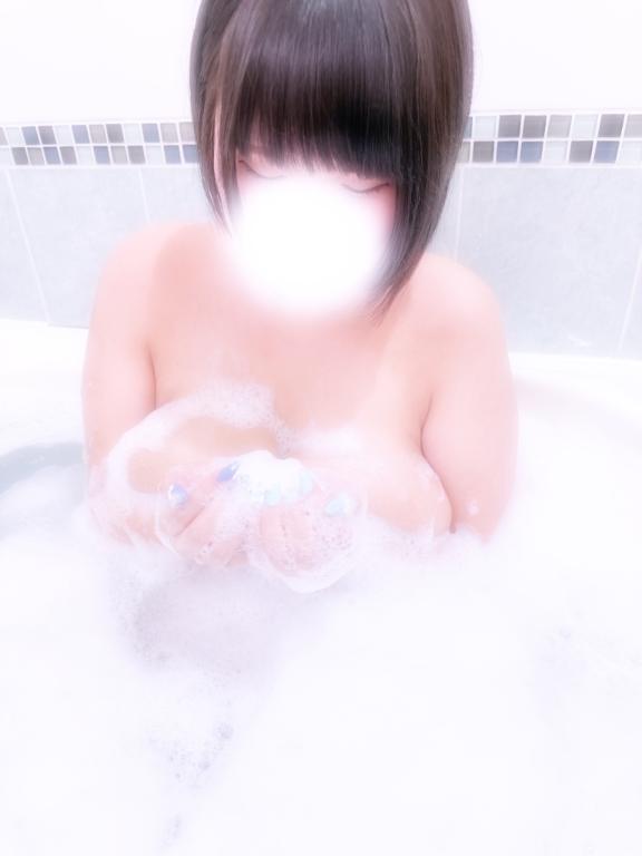泡のある浴槽で両手に泡をのせたボブヘアの女性。顔は白くぼかされている